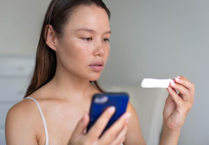 A woman waiting for pregnancy test results, holding her phone 