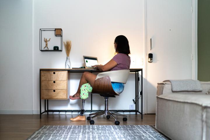 A woman sits at a home office desk
