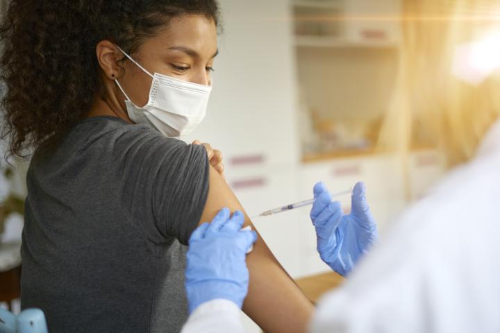 Woman wearing a mask having a Covid-19 vaccine