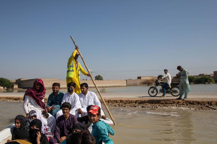Image of people using boats to cross floodwaters in Johi, Pakistan, during severe flooding in October 2022