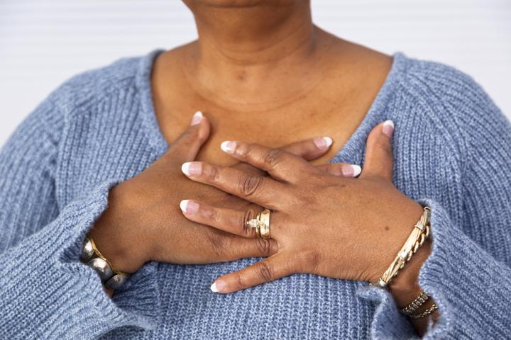A woman places her hands on her chest