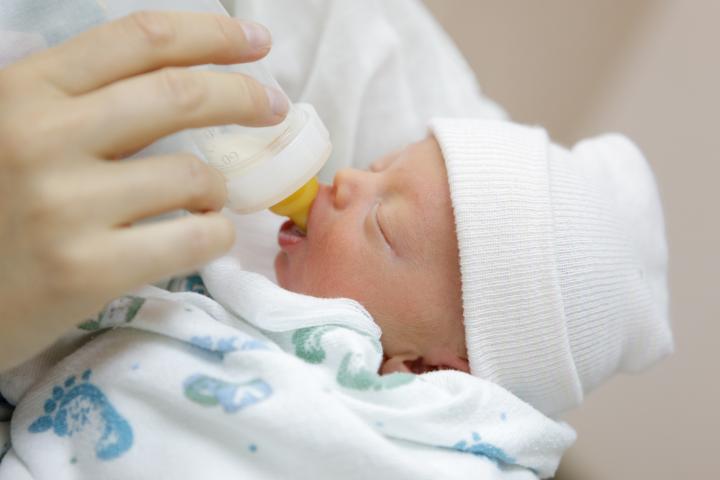 Premature baby being fed with a bottle in the hospital nursery