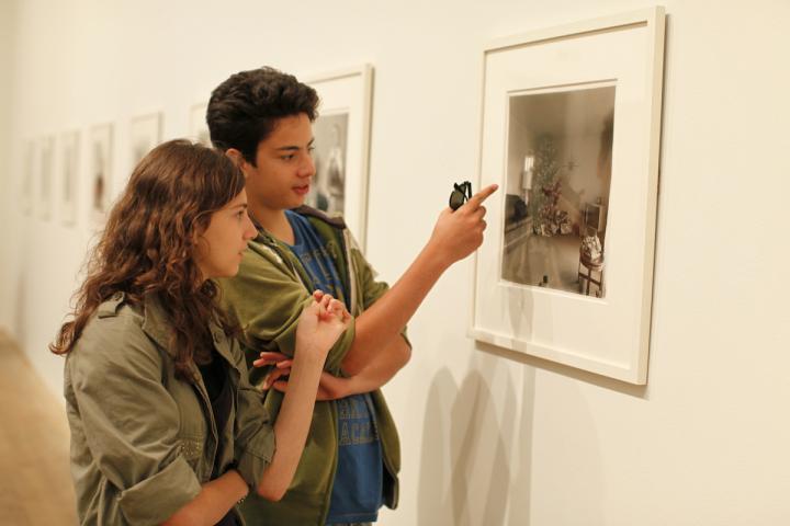 Two people examine a piece of art in a gallery