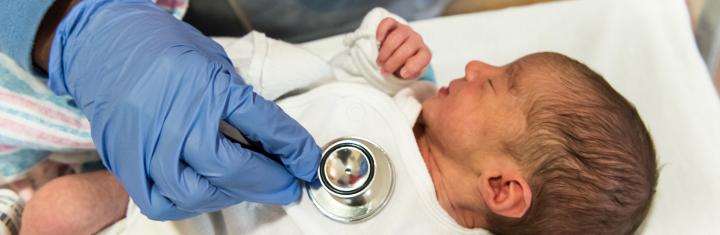 Health worker checking the heart of a newborn baby in hospital
