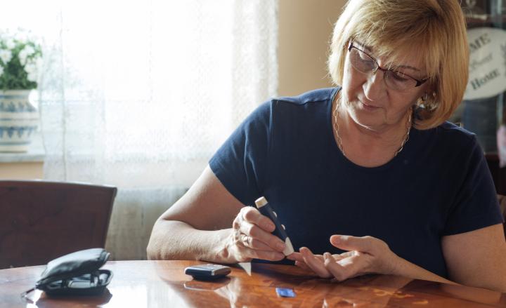 Senior woman checking blood sugar level with test at home
