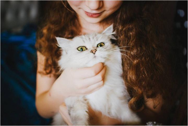 Girl holding cat that looks uncomfortable