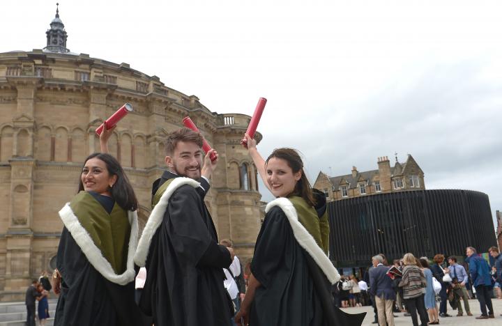 Three students in graduation robes outside McEwan Hall