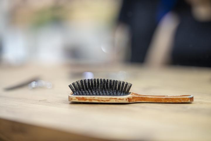 Photograph of a wooden hair brush with black bristles lying on a table. 