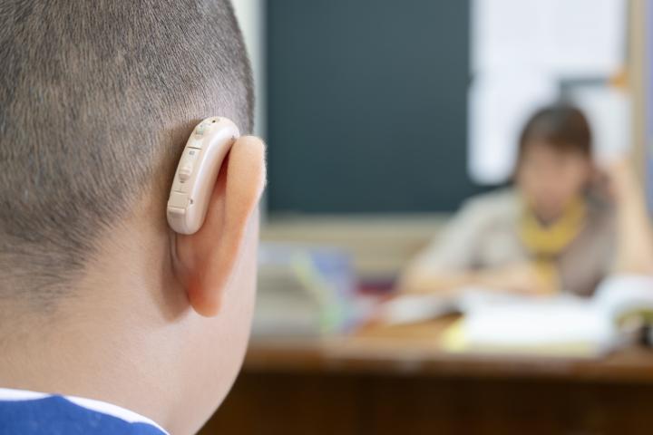 Student with hearing aid listens to teacher in class.