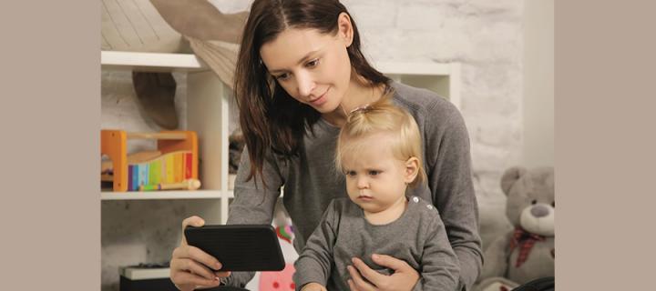 a woman looking at a phone screen, with a child sitting on her lap