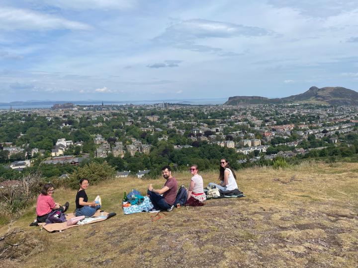 Members of the Hetherington lab sitting outside for a picnic with a view over Edinburgh