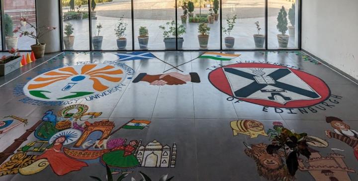 Colourful Rangoli designs depicting GBU and University of Edinburgh logos and a handshake motif