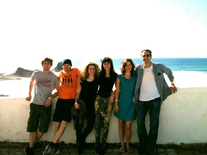 Lab group members pose for a group photo in front of a wall overlooking the sea