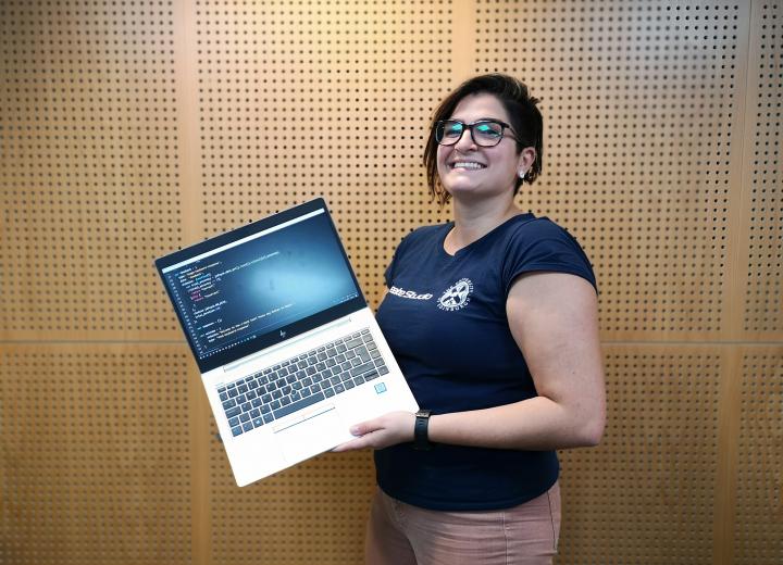 Carine Abraham, Student Evaluation Assistant, holding her laptop