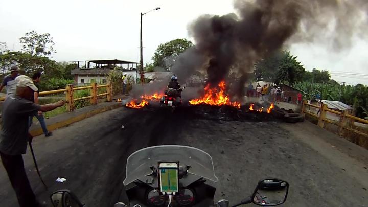 Matthew Lee motorbiking through a flaming barricade in Ecuador