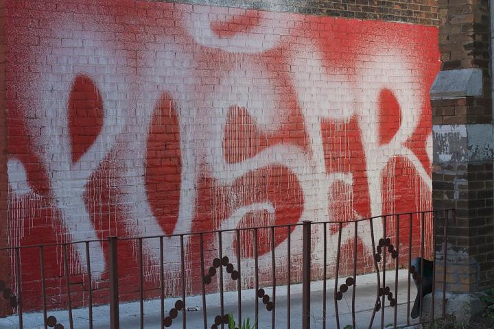 Photograph of spray paint on a red wall. 