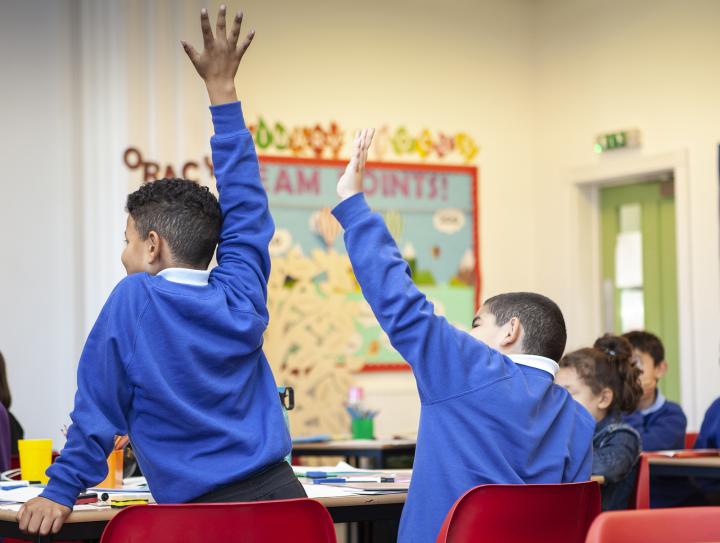 School pupils with their hands up in class