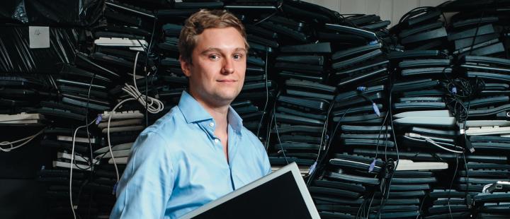 James Turing standing in front of a high stack of used PC hardware