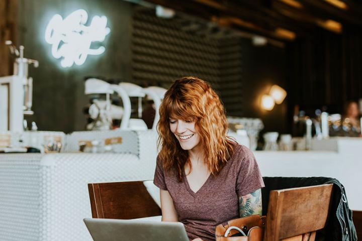woman smiling using laptop in a cafe