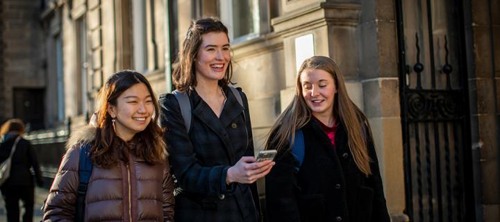 Three female medical students on an Edinburgh street, sharing a joke