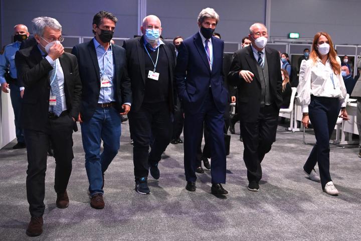 Group of 5 men and 1 woman walking in a line with masks on at COP26. 