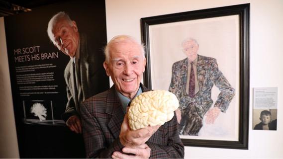 Lothian Birth Cohort participant with potrait and model of brain at exhibition