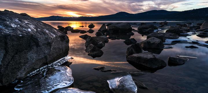 Image of the sea at sunset, with lumps of ice flow in the foreground