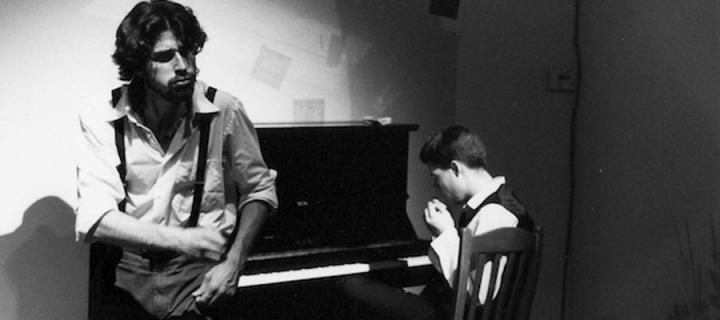 Film still of boy at piano and man standing