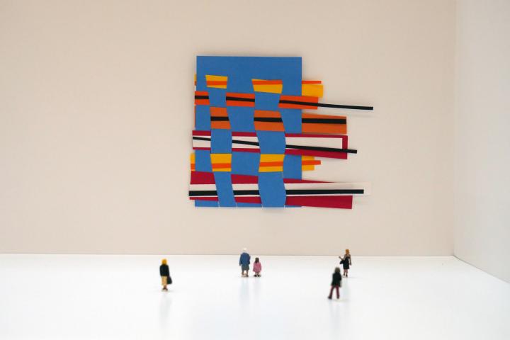 Photo of a small-scale exhibition model with a piece of paper weaving on the wall.