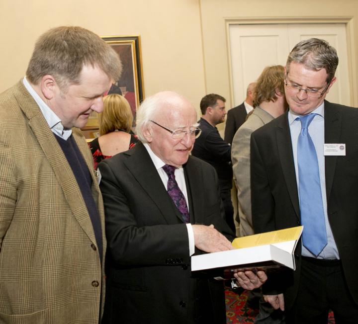 Photo showing President Higgins looking at a book presented to him by Professor Jackson.