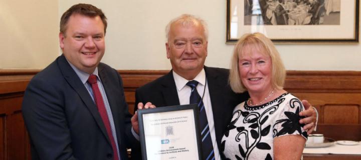 Sir Tom Devine receives his award from Nick Thomas-Symonds, MP alongside Catherine Devine