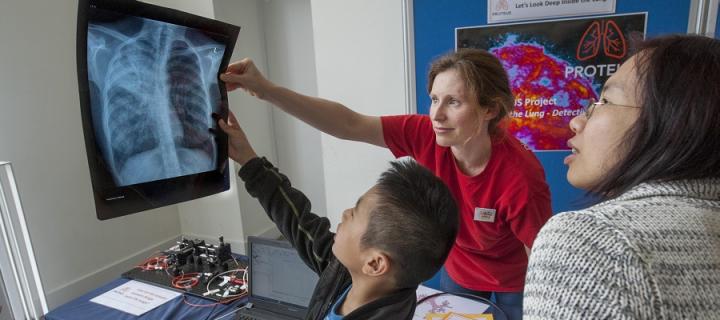 Researcher explains image to visitors at Edinburgh International Science Festival