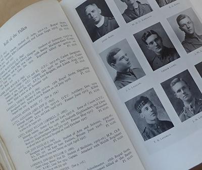 Book open to page with the title of 'Roll of the Fallen' and text on left and nine black and white photos on the right. 