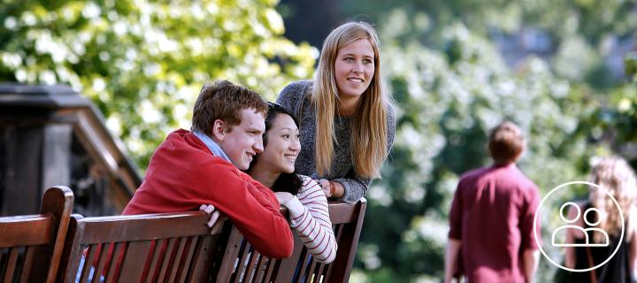 A group of students sitting on a bench in a park