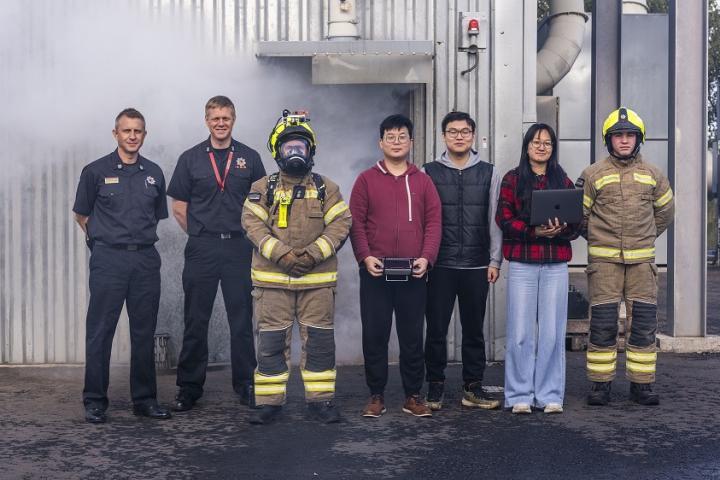 A group photo showing a line of people: firefighter in their gear and young researchers