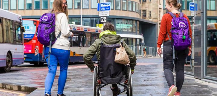 Simon community - three people walking and wheeling down a Scottish street
