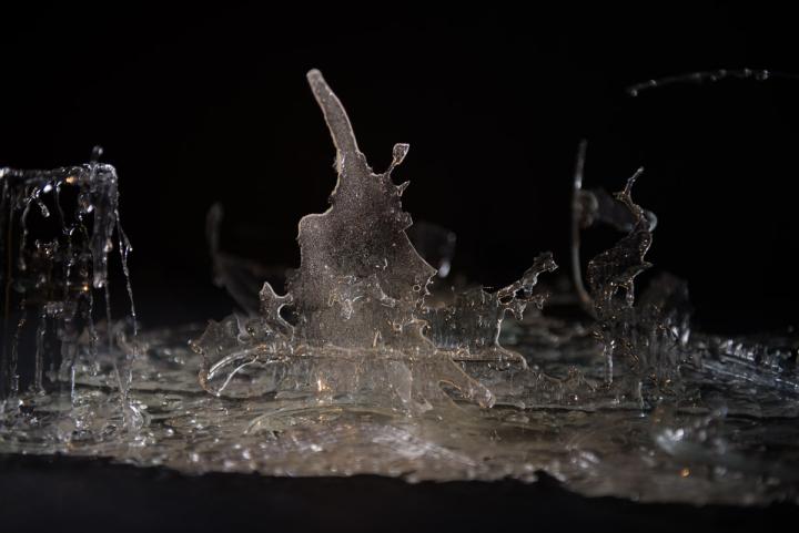 Photograph of a glass sculpture in front of a black background.
