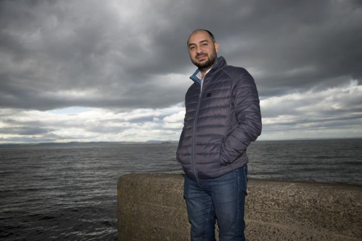 Photograph of Dr Amer Masri standing at the end of Fisherrow Harbour near the town of Mussleburgh
