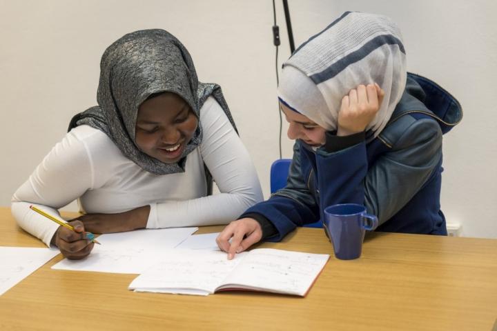 Photograph of Esti Zaid tutoring a student: both are sitting at a desk working together. 
