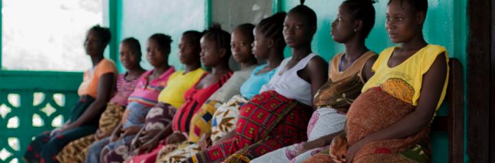 Pregnant women sitting in a row outside a Liberian 'waiting home'