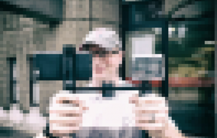 A pixelated image of a man holding a mobile phone