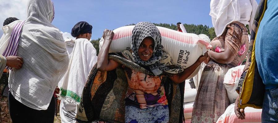 Ethiopian woman carrying sack of crops