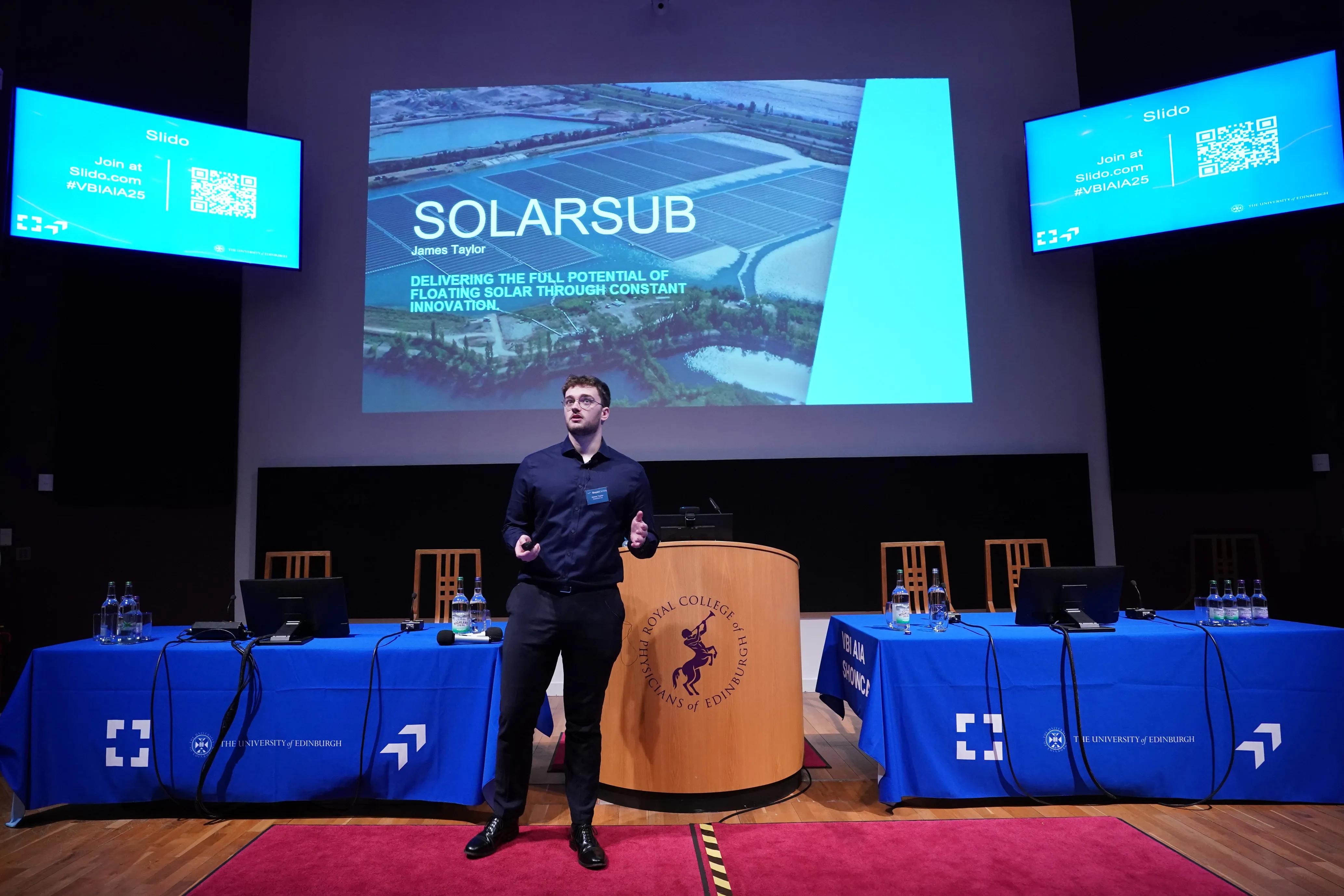 Presenter standing in front of screen saying 'SolarSub'
