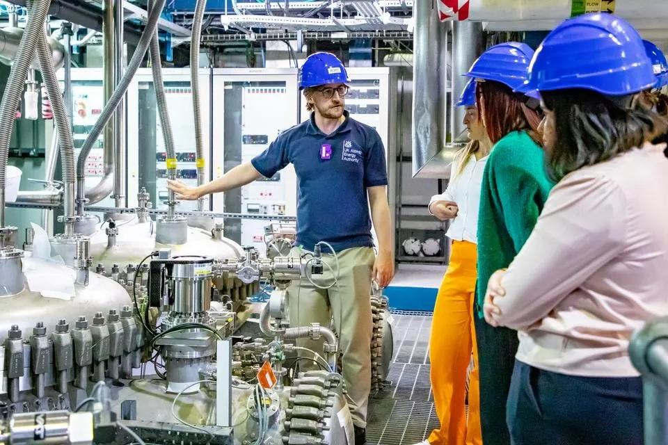 Group of people wearing hardhats being shown scientific equipmenttechnology