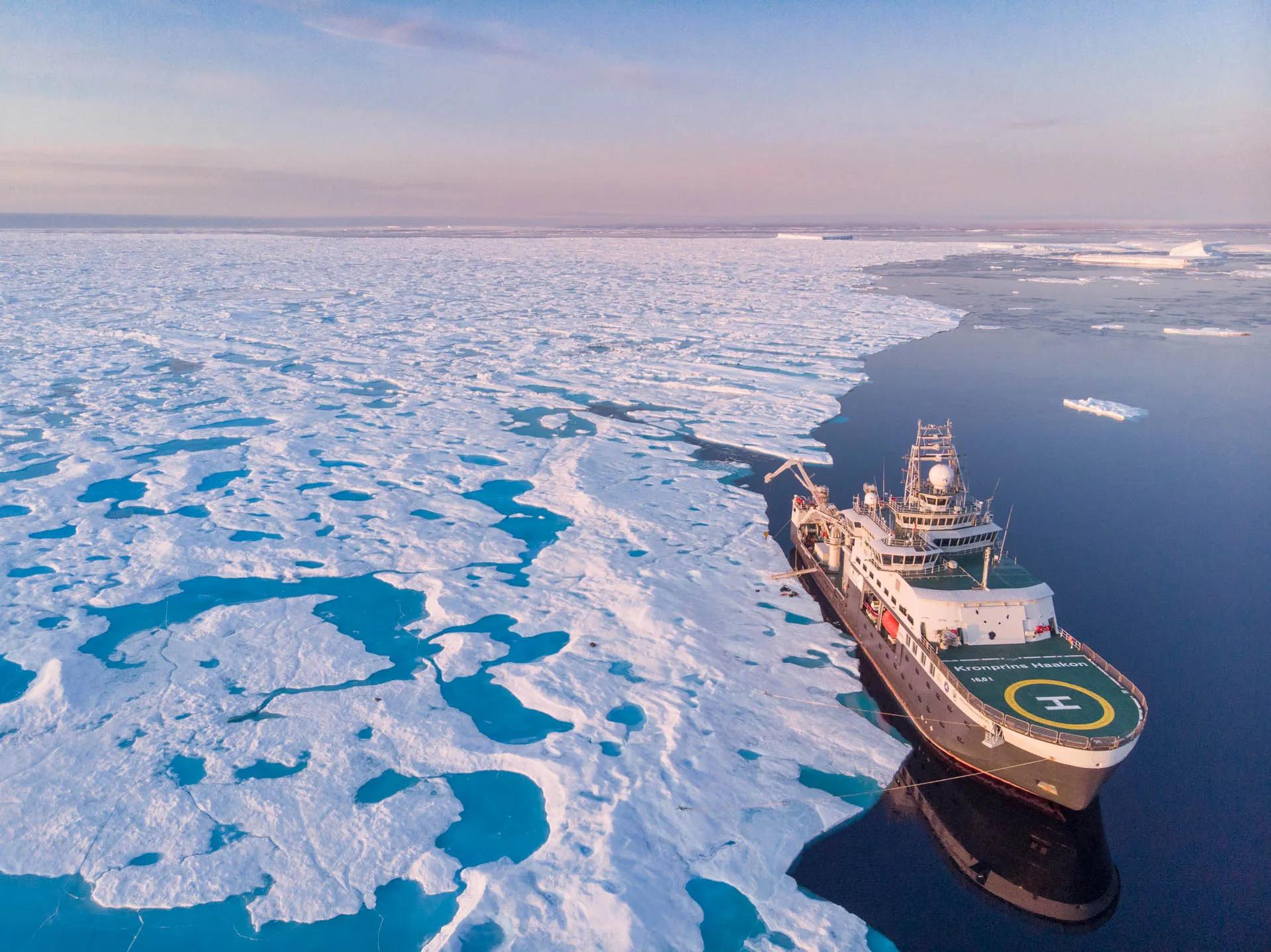 Aerial view of research ship next to very large section of sea ice