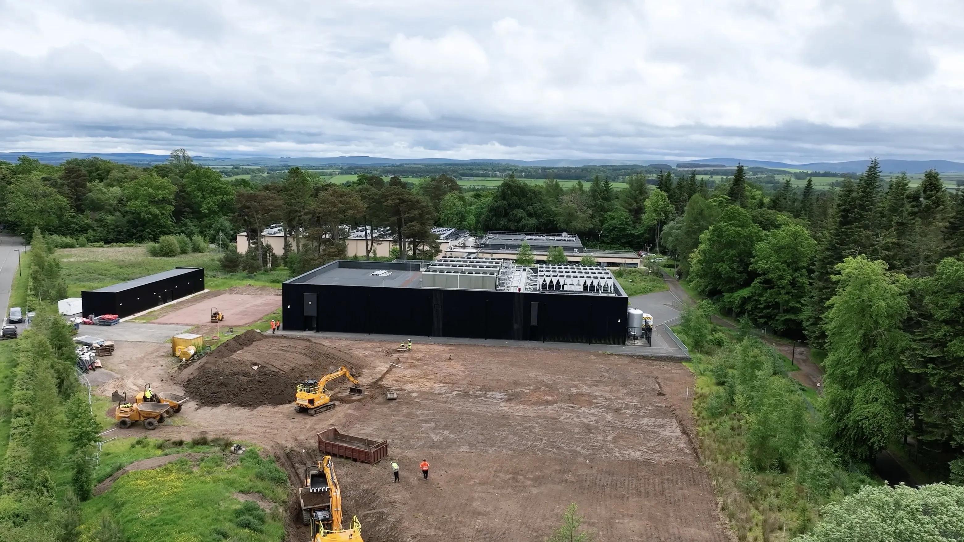 An aerial view of a large construction site surrounded by trees