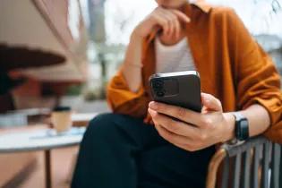 Close up shot of a person using a smartphone while sitting at a table