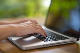 Blurred close-up image of person typing on a laptop