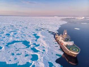 Aerial view of research ship next to very large section of sea ice