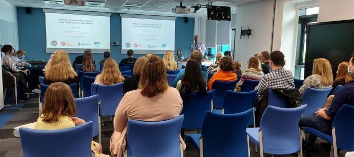 Seminar room full of people, facing a screen